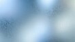 © Enigma - Frosted ice glass surface showing blue and white gradient lighting with shimmering bokeh effect creating an abstract window texture background
