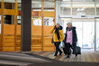 © .shock - Two older women dressed in winter clothing standing in a hotel lobby and having a friendly conversation next to their luggage. Concept of travel, friendship, and leisure lifestyle for seniors.