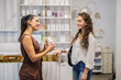 © PintoArt - Retail assistant explaining skincare product to smiling customer