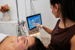 © PintoArt - Cosmetologist analyzing client's skin with advanced facial technology