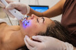 © PintoArt - Woman receiving microcurrent facial treatment for skin rejuvenation