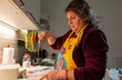 © Diego - Woman wearing apron whisking ingredients in kitchen
