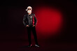 © deagreez - Stylish santa rocker in leather jacket with white beard and sunglass under red spotlight for festive holiday stock photo