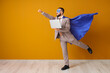 © Pixel-Shot - Young businessman dressed as superhero with laptop on orange background