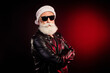 © deagreez - Cool Santa rocker in a leather jacket with white beard and dark sunglass standing against a red glow festive mood and Christmas spirit