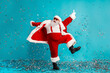 © deagreez - Santa Claus dancing in a bright blue studio with confetti perfect for Christmas campaigns and holiday promotions