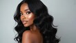 © Maryna - Beautiful dark skinned woman shows wavy black hair. Attractive female model with perfect makeup and shiny skin smiles. Elegant beauty studio portrait for fashion magazine.