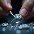 © Maryna - Goldsmith sets diamond in ring. Jeweler polishes precious stone. Hands work with jewelry tool. Craftsperson produces luxury engagement ring in workshop. Gemstone ring production, repair process.