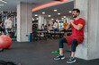 © Dorde - Indoor gym brightly lit male exercising wall sit strength training with modern fitness equipment