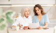 © JackF - Elderly woman and adult woman discussing agreement while sitting at table in kitchen