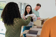 © Wavebreak Media - Diverse volunteers sorting and packing garments in living room on table by sunlit window with boxes