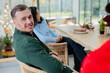 © Wavebreak Media - Friends wearing casual winter attire sitting at wooden table laughing and sharing festive meal
