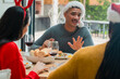 © Wavebreak Media - Diverse friends sitting around table in dining area wearing Santa hats sharing bread plates wine