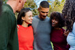 © Wavebreak Media - Diverse friends standing shoulder-to-shoulder in park wearing casual sweaters smiling together