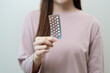 © KMPZZZ - Contraception and pregnancy, menstruation concept, birth control pills asian young woman hand holding hormonal oral contraceptive medicine, take pharmaceutical to prevention, safe virus sex disease.