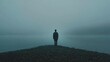 © Sifat - Lonely man standing on misty pebble shore looking out over tranquil cold lake water