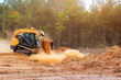 © ungvar - Yellow skid steer works on construction site, moving dirt clearing trees in forested environment.