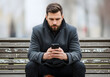 © Anim - bearded man sitting on bench using smartphone outdoors