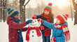 © Milan - Happy diverse children building a snowman together in a snowy park. Multiethnic friends having fun playing outside in winter during snowfall. Childhood friendship concept.