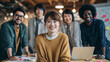 © 菊池恵子 - A cheerful young Japanese businesswoman smiling at the camera during a creative team meeting.