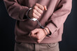 © New Africa - Man in handcuffs on black background, closeup
