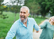© Lumos sp - Happy active mid aged adult couple having fun walking running holding hands and bonding in park or nature outdoors