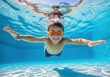 © Ozz - Young boy swims underwater in a swimming pool with orange goggles