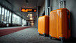 © ABF_MATEO - Two orange suitcases stand ready for travel at a modern airport terminal, hinting at adventures and future destinations.