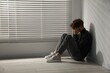 © New Africa - Depressed teenage boy near window at home, space for text