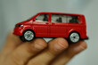 © vegefox.com - Detailed shot of a miniature red van held in a person's hand. Focus on the toy's details and the hand's texture. The blurry background adds dept