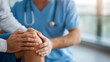 © Denis Yevtekhov - Physiotherapist examining knee joint during therapy defocused clinic, faceless rehabilitation session, orthopedic visualization detail, blurred modern background, treatment concept