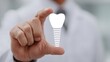 © Shobakh - Medical professional showcases a luminous white dental implant model between their fingers