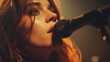 © GreenOptix - A female rock singer with long chestnut hair performs passionately on stage, conveying deep emotion under soft golden-orange lighting