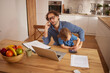 © Stockphotodirectors - A father talks on the phone while his young child plays on a laptop, showing a moment of family interaction and shared activities at home.