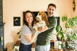© Louis-Paul Photo - Portrait of beautiful couple stand, smile and hug at home with basset dog