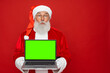 © InsideCreativeHouse - Surprised Santa Claus man in Christmas hat red coat holding using laptop pc computer showing demonstrate blank empty screen isolated on red background copy empty space