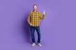 © deagreez - Young handsome guy in yellow plaid shirt jeans smiling and pointing up against purple background for lifestyle fashion advertising