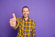© deagreez - Young handsome guy in checkered yellow shirt gives a thumbs up against a purple backdrop