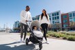 © Виктория Марьенко - African American parents walk city sidewalk, pushing baby in stroller, enjoying sunny day together.