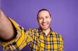 © deagreez - Young handsome guy smiling in a yellow checkered shirt against a purple background for lifestyle and advertising concepts