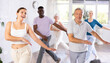 © JackF - Portrait of cheerful young girl enjoying active dancing during group training with adults people of different ages in dance studio