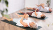 © JackF - Mature woman at group yoga class does warm-up, stretching. Lady is lying on back, bent one leg at knee and raised it to chest