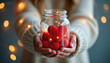 © miss irine - Woman hands holding jar filled with red hearts. Symbol of love emotion gratitude thanks. Bokeh lights glow create festive warm mood. Concept of holiday charity well being and care.