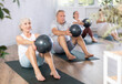 © JackF - Elderly woman doing pilates with soft ball in group on mat in fitness studio