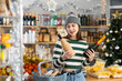 © JackF - While shopping on eve of New Year holidays, young lady buys alcohol for festive party. Buyer holds basket filled with products, selects suitable product from wine assortment
