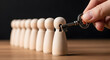 © Pixel Studio - Hand inserts a vintage key into a wooden figure representing unlocking potential talent management and finding solutions within a team or organization on a wooden surface