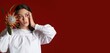 © Pixel-Shot - Beautiful young Asian woman with protea flower on red background with space for text