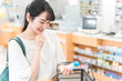 © buritora - A woman shopping for disinfectant, mouthwash, cleaning solution, insect repellent, and over-the-counter medicines at a pharmacy/drugstore