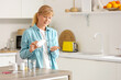 © Pixel-Shot - Mature woman taking vitamin supplements in kitchen