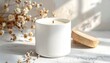 © Nurita - White ceramic candle with wooden lid, delicately accented by dried flowers and natural light, casting soft shadows for a minimalist, serene home decor display